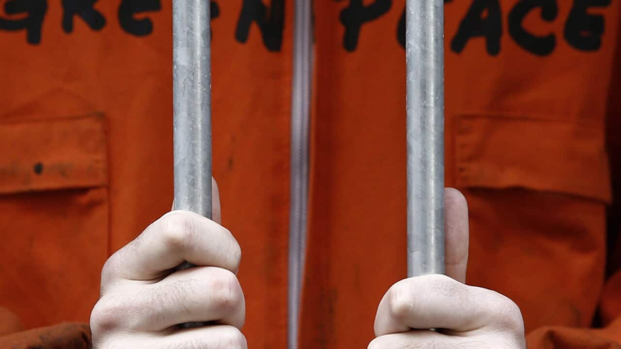 A close-up of the handcuffed hands of a Greenpeace activist.