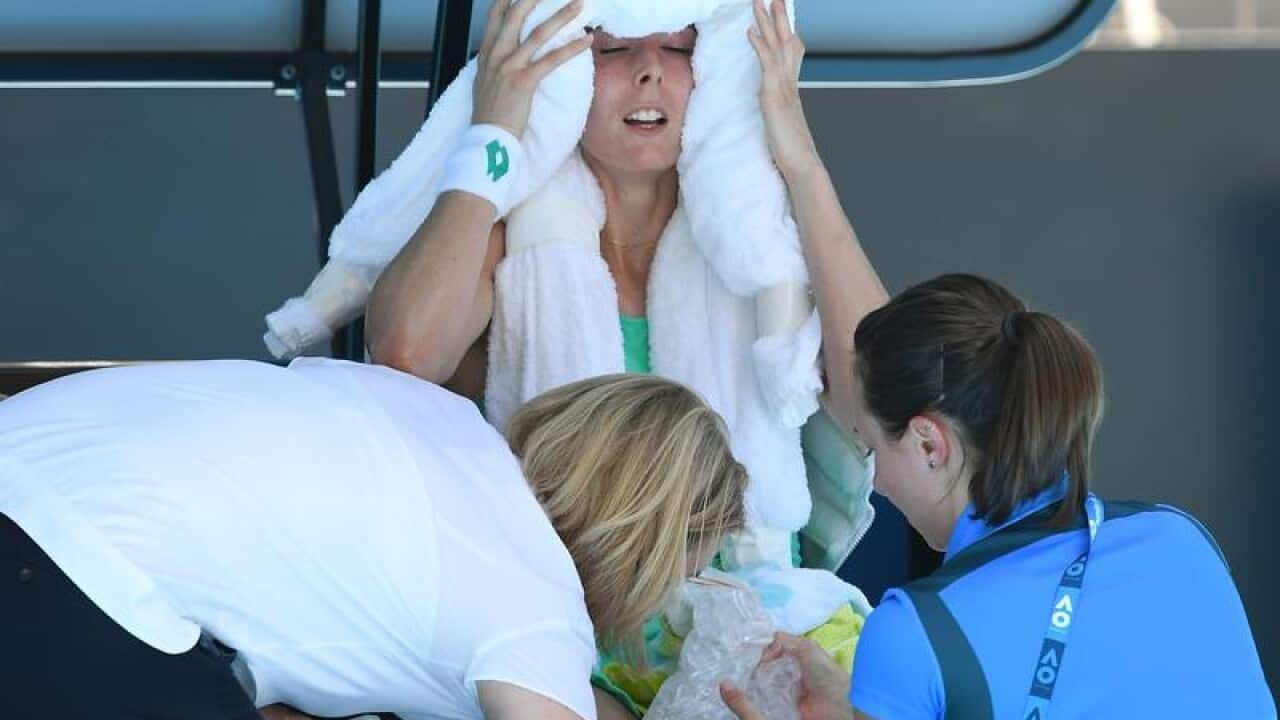Alize Cornet of France holds a towel to her face