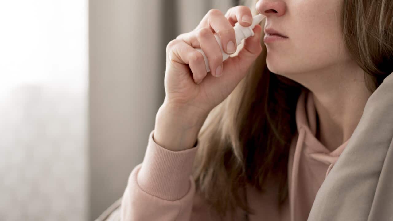 woman taking nasal spray treatment