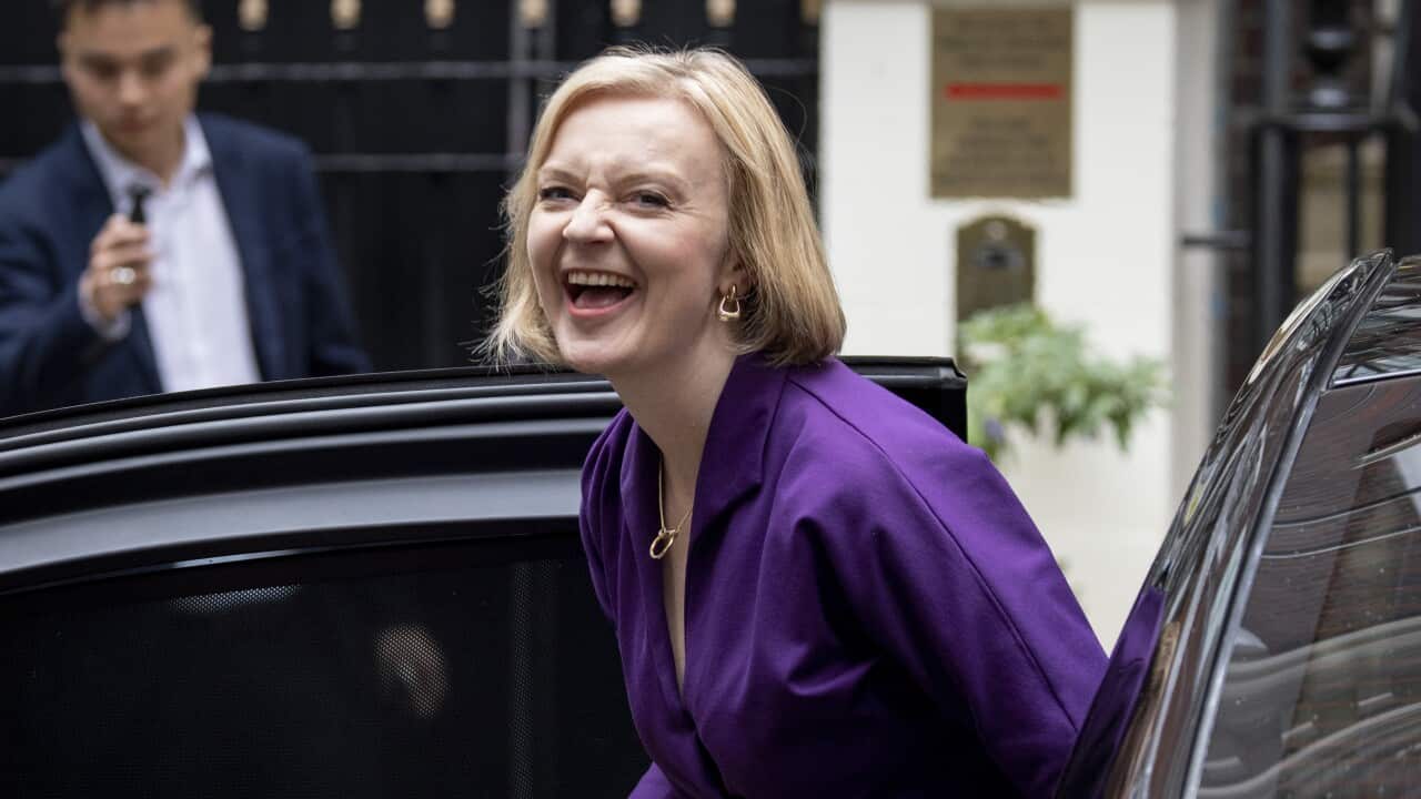 A woman laughs as she steps out of a car