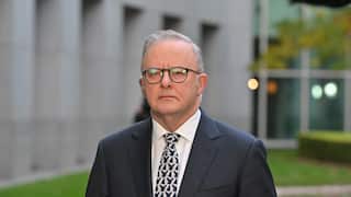 A man in a suit and a tie wearing glasses looks on