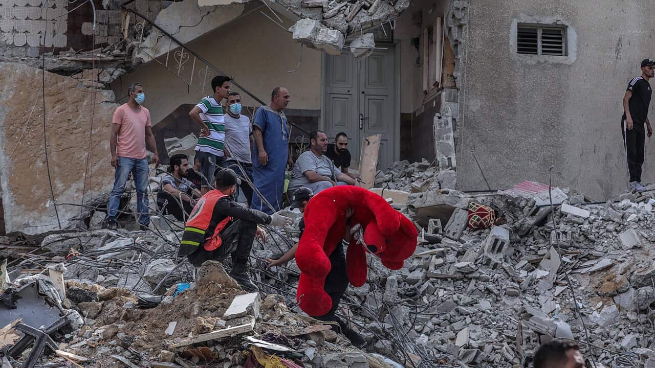 A Palestinian holds a teddy bear among destroyed homes in Gaza City