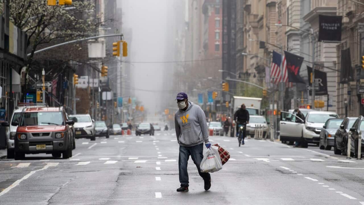 A man wearing a facial mask walks across the middle of 5th Avenue in Midtown Manhattan of New York, Sunday, March 29, 2020. AAP Image/AP Photo/Mary Altaffer