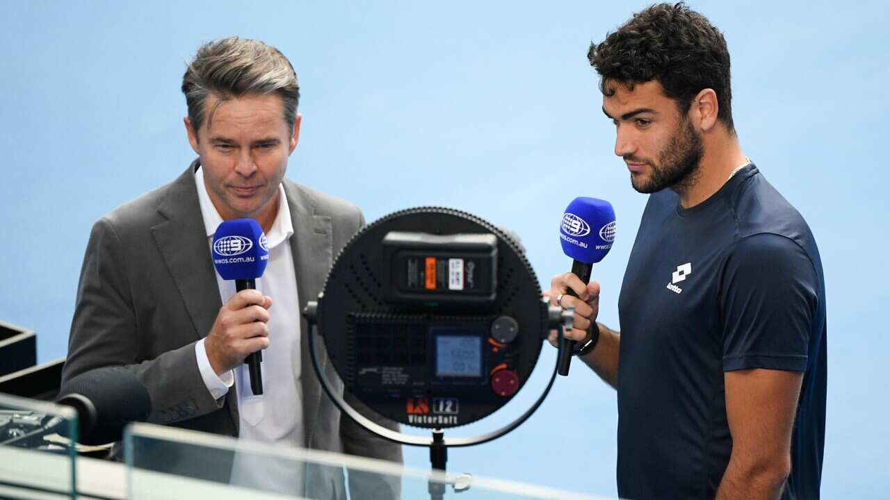 Italy's Matteo Berrettini, right, is interviewed by former Australian player Todd Woodbridge after he withdrew from his fourth round match against Greece's Stefanos Tsitsipas with an injury at the Australian Open tennis championship in Melbourne, Australi