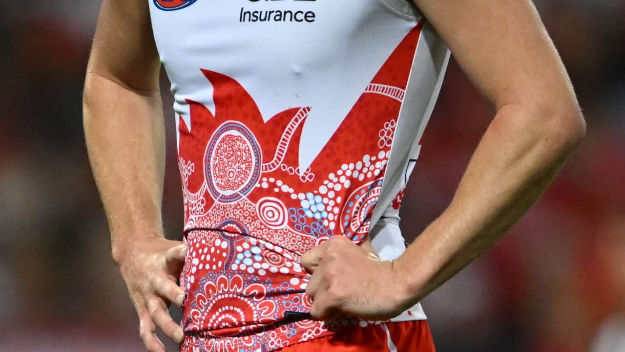 A Sydney Swans' player wearing a red AFL jersey with Indigenous art on it. The player's face cannot be seen.