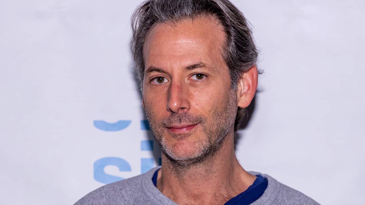 A man in front of a grey background.