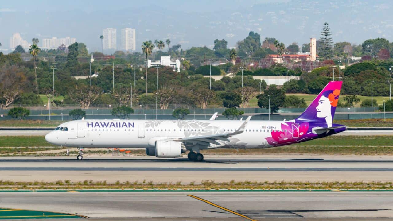 A Hawaiian Airlines airbus on a runway before taking off from an airport.
