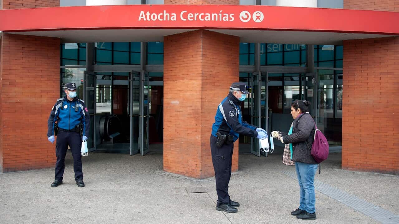 Police officers hand out masks to workers at Atocha train station in Madrid, Spain, April 14, 2020.