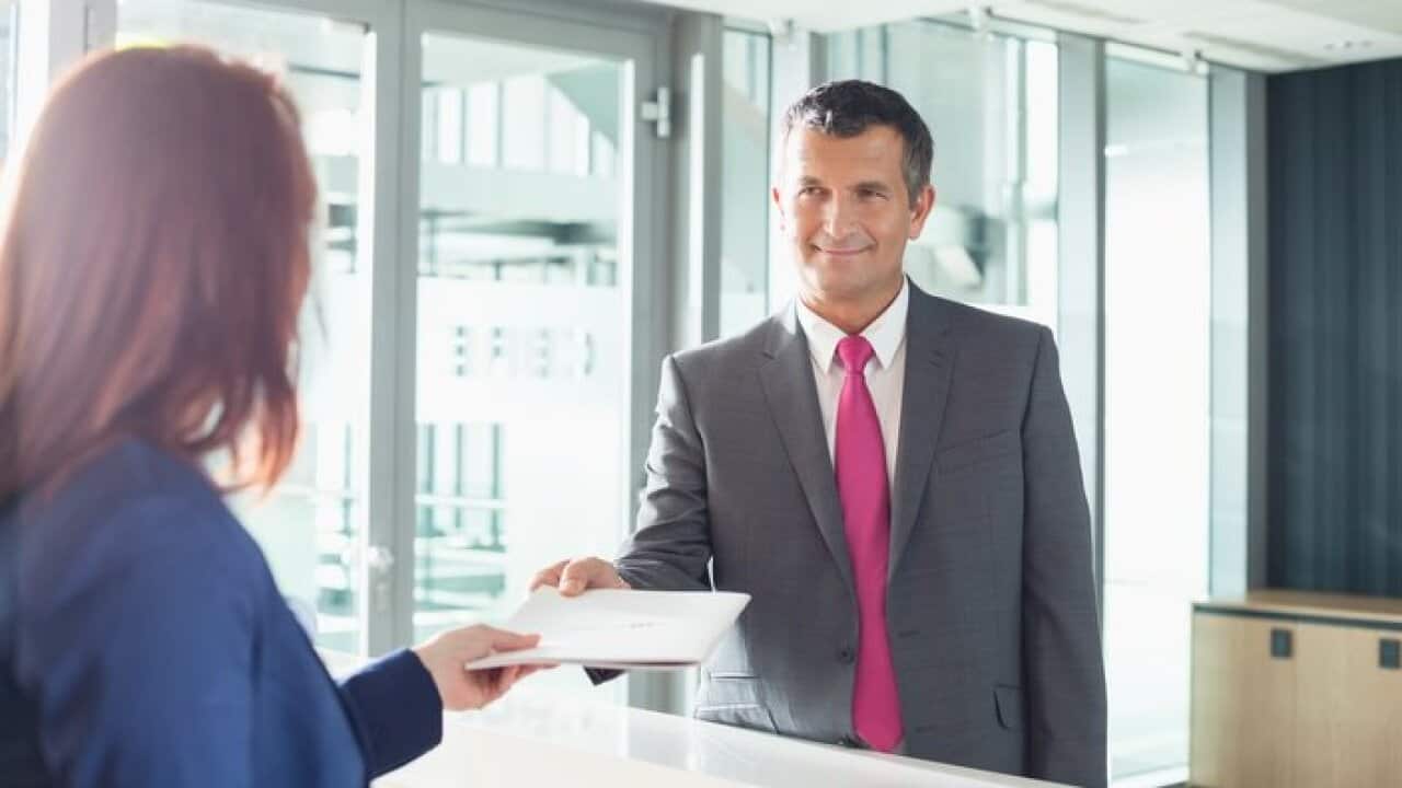 Businessman receiving document from receptionist in office