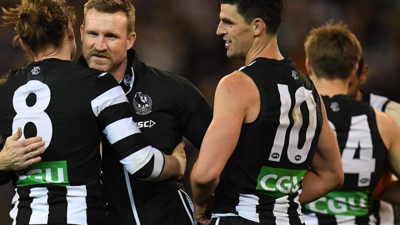 Magpies coach Nathan Buckley (second from left) embraces Tom Langdon