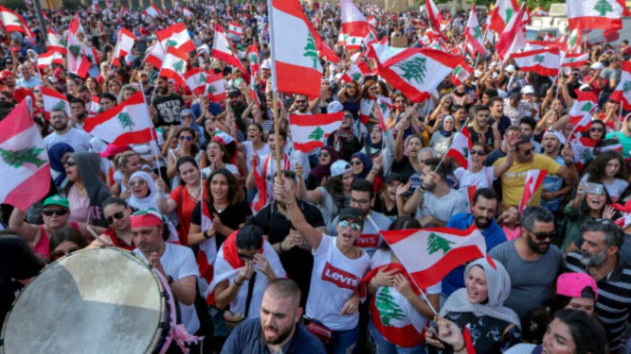 Protesters wave flags during a protest in front of the government palace in downtown Beirut, Lebanon.