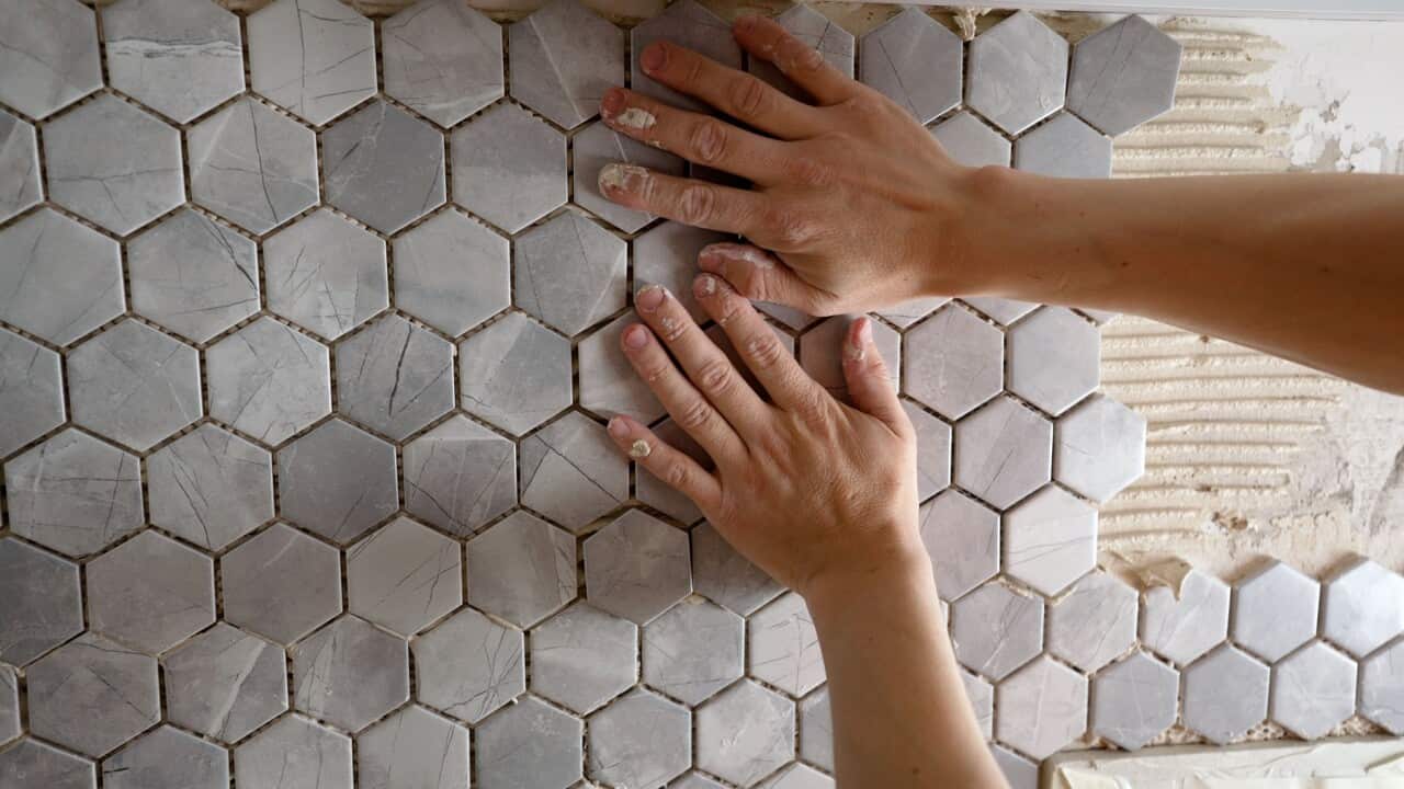 Hands on tiles in bathroom