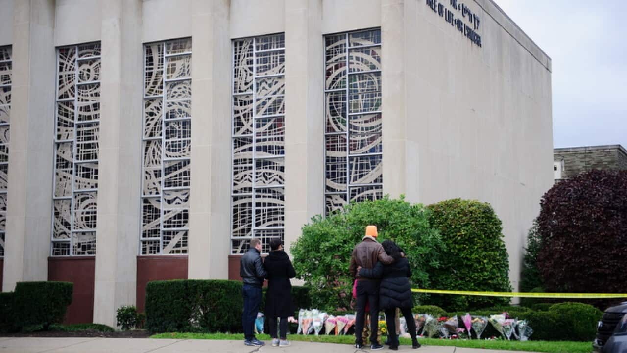 Mourners place flowers in frong of sinagogue