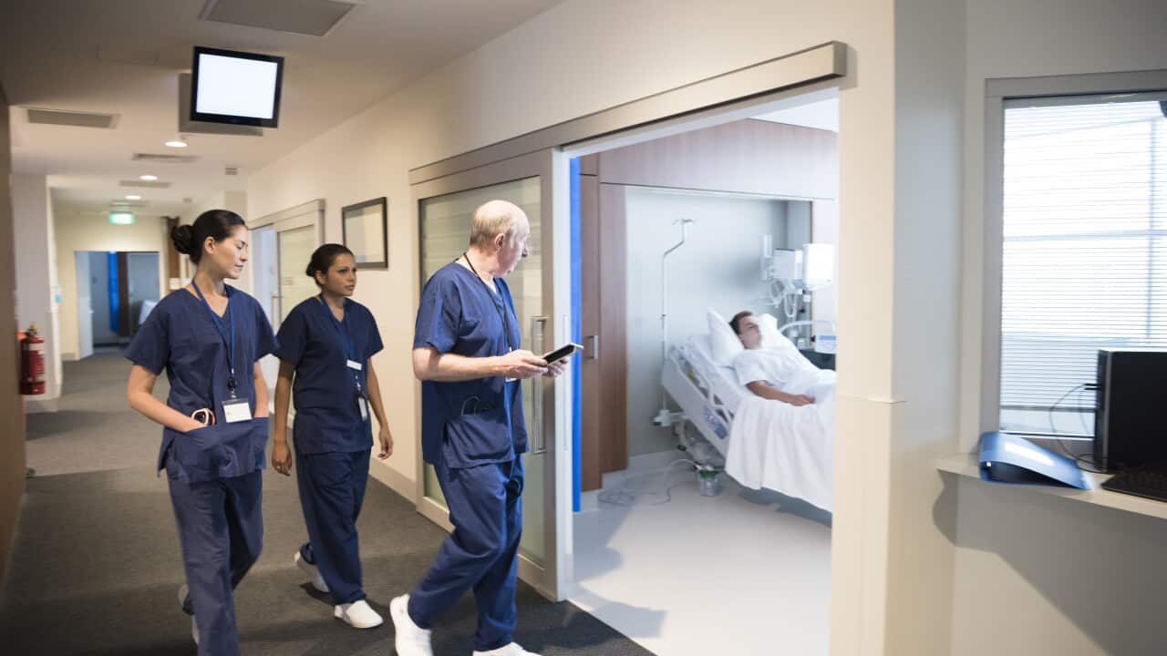 Medical staff in hospital corridor with patient in bed