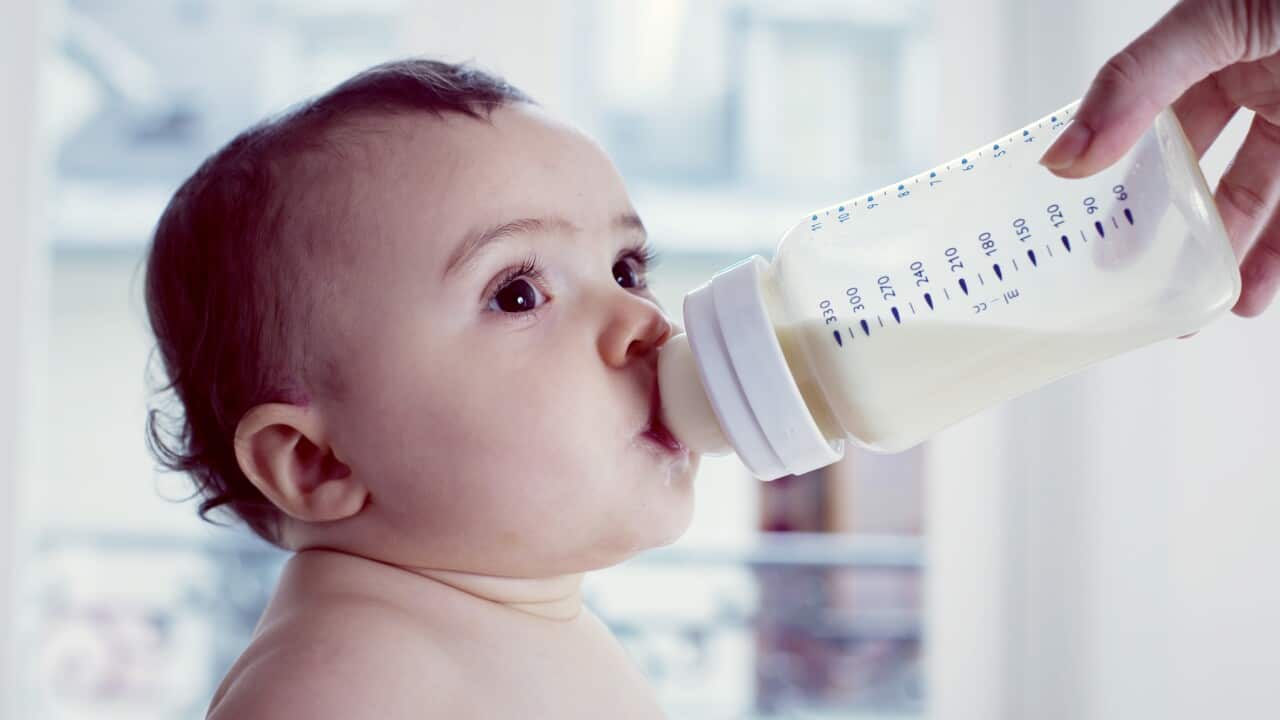 Infant drinking milk from baby bottle