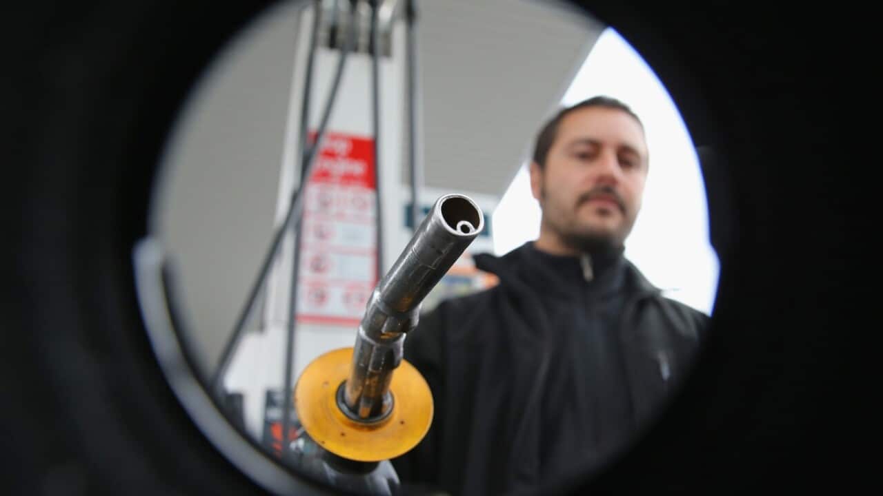 A man uses a fuel dispenser to fill his car up with petrol at a petrol station