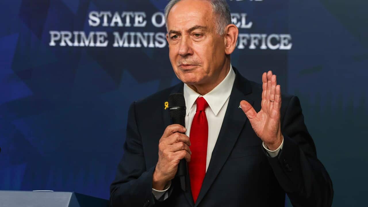 Israeli Prime Minister Benjamin Netanyahu standing and speaking into a microphone.