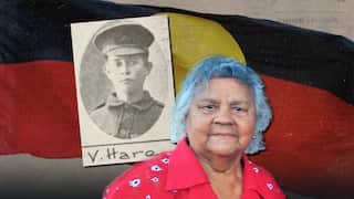 A cut-out of a veteran soldier and a woman. The Aboriginal flag is in the background.
