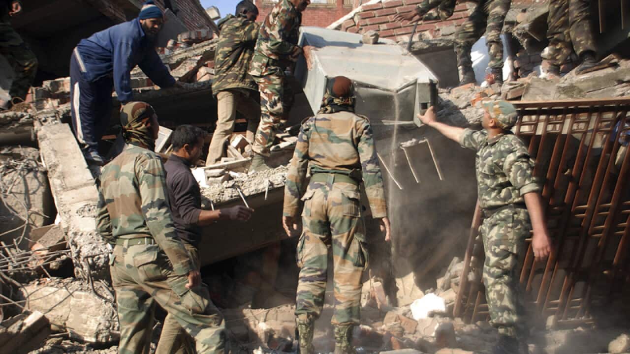 Indian soldiers remove debris from a damaged building