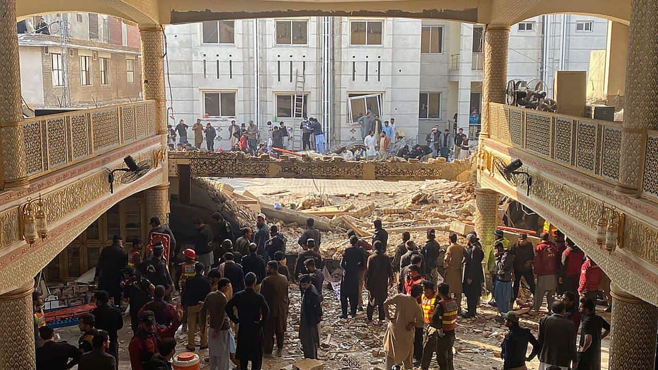 People look at the destruction of a mosque.