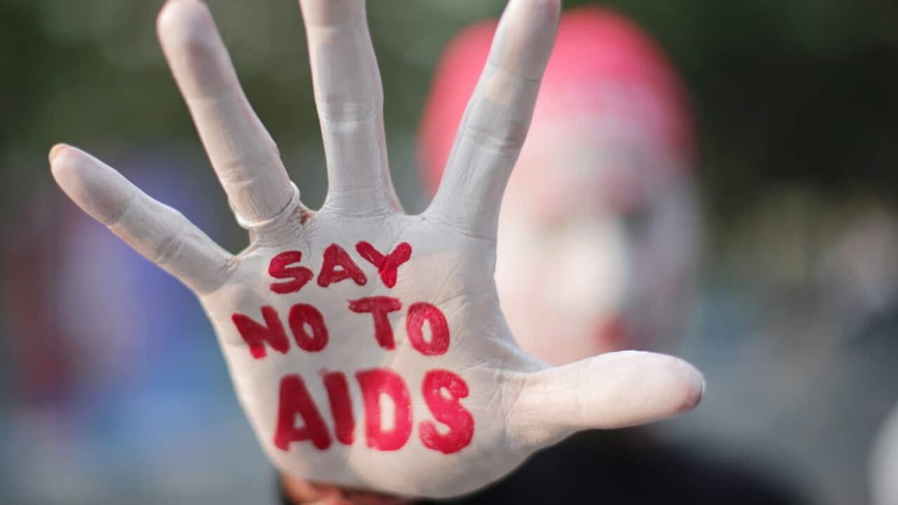 An activist paints his hand with an AIDS awareness message