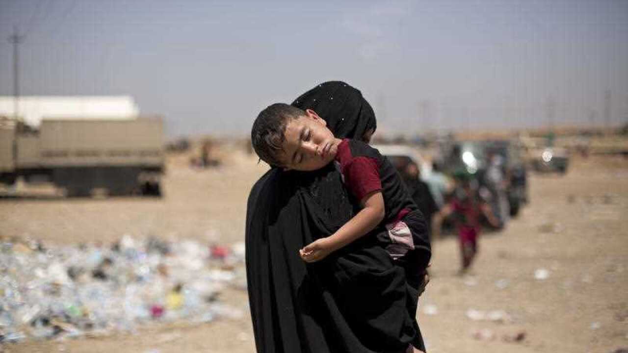 A child sleeps on his mother's shoulder after a perilous journey on foot to flee heavy fighting in their west Mosul neighborhood.
