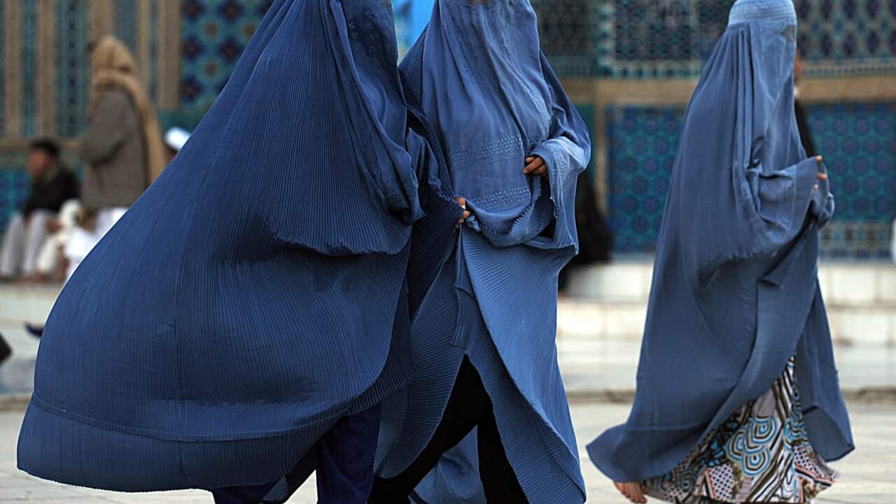 Burqa-clad women walk at the Hazrat Ali