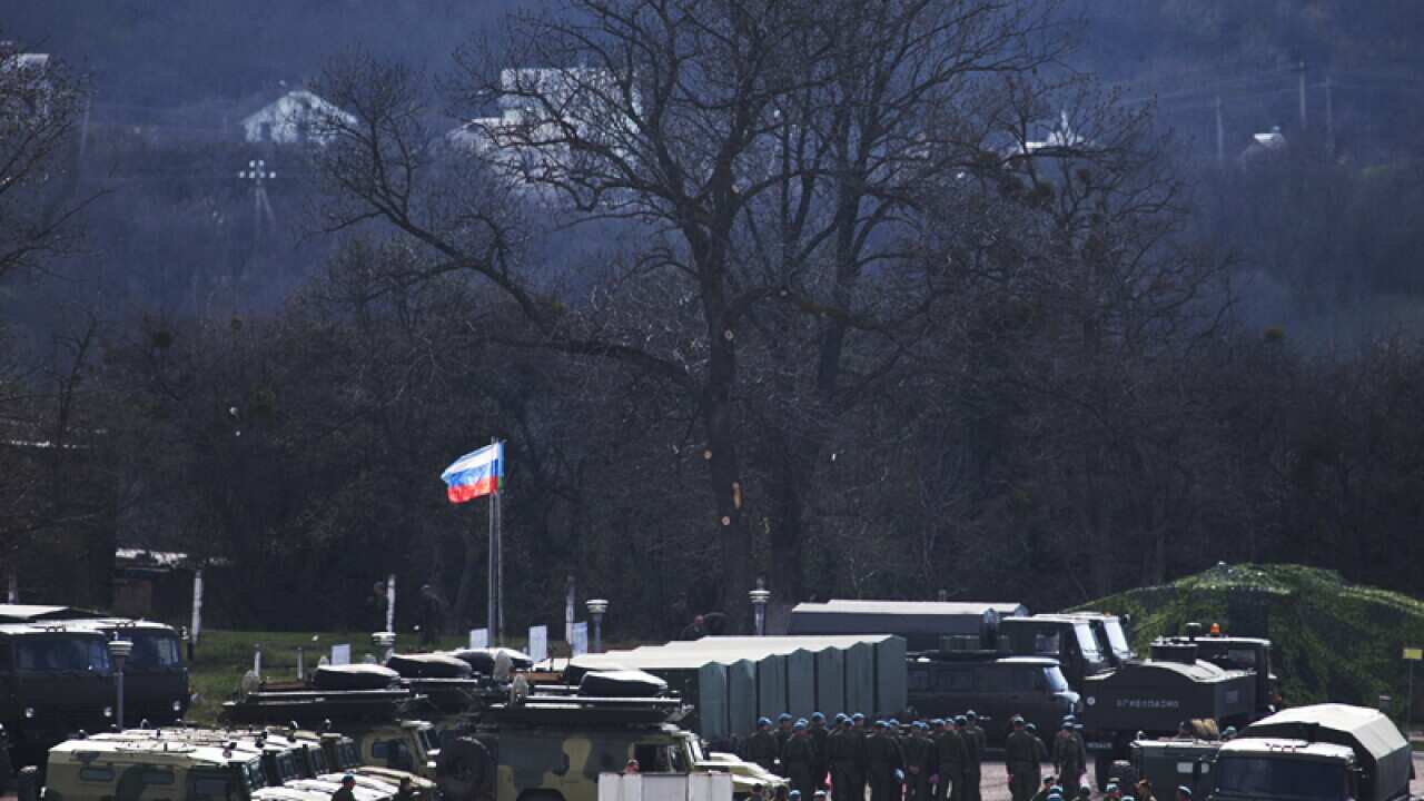 A Russian national flag flies over Russian troops.