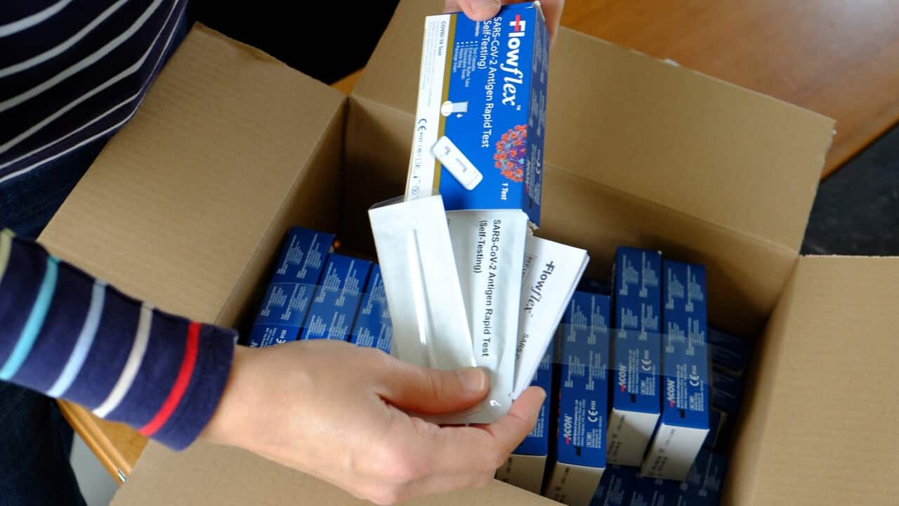A woman unboxing a postal package of Rapid Antigen Tests for self-testing.