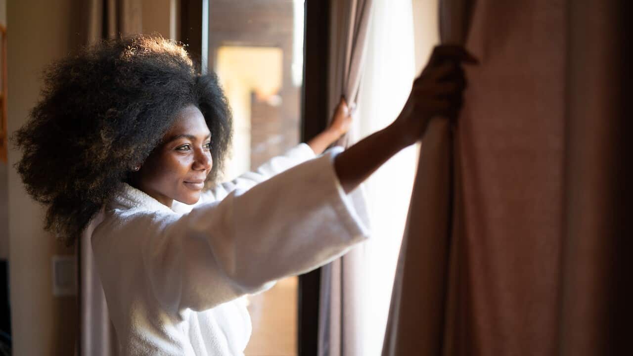 Woman pulling curtains in hotel room