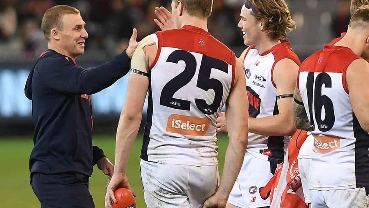 Coach of the Demons Simon Goodwin (left) embraces his players