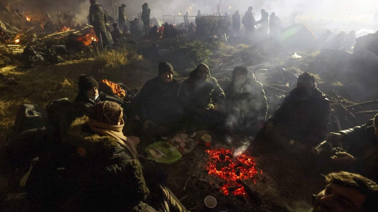 Migrants warm themselves near a fire at the Belarus-Poland border