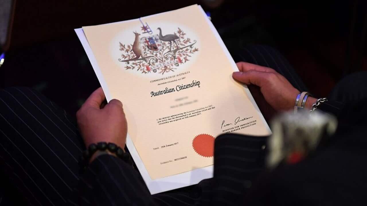 An Australian citizenship recipient holds his certificate during a citizenship ceremony on Australia Day in Brisbane