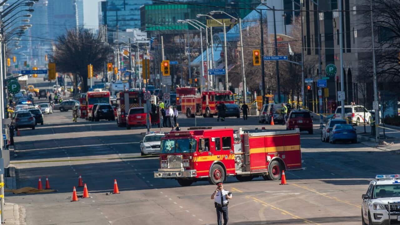 A Toronto police officer stands near a covered body (L) on Yonge Street in Toronto, in northern Toronto, Canada, 23 April 2018. 