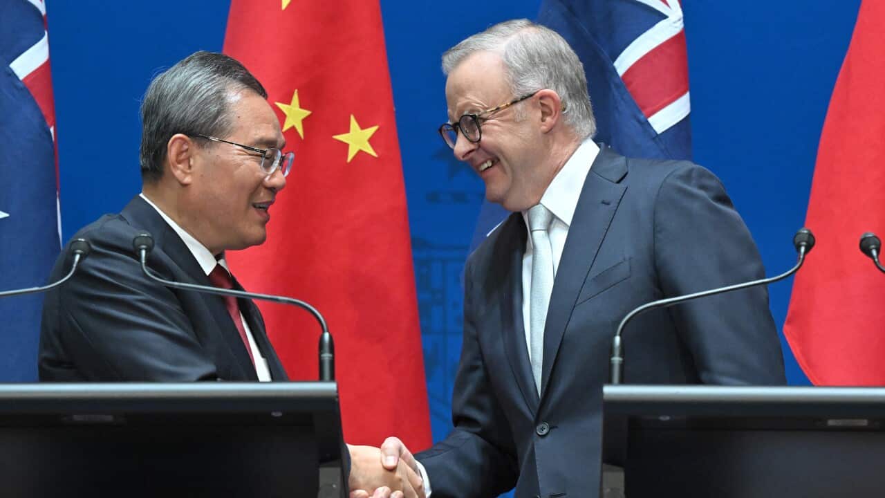 Two men in suits shaking hands and smiling.
