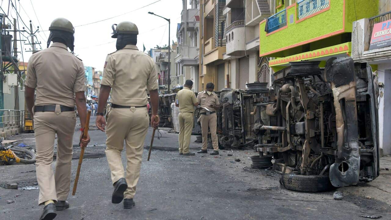 Policemen stand guard next to burnt police vehicles along a street in Bangalore.