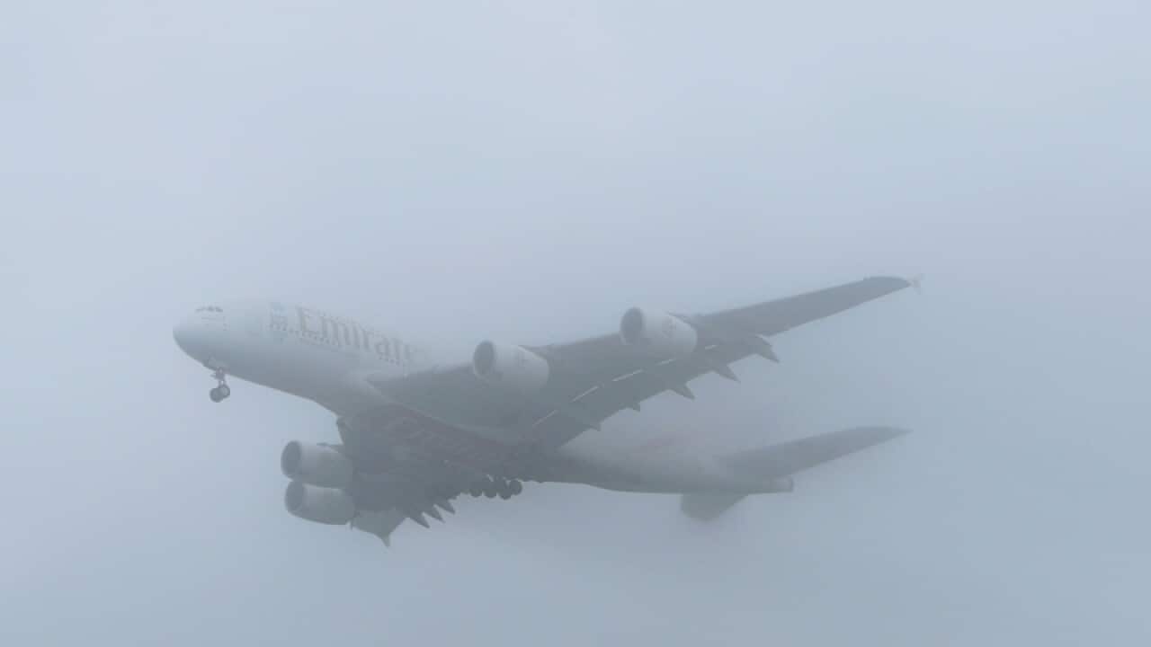 An Emirates plane comes into land through the fog at Heathrow Airport