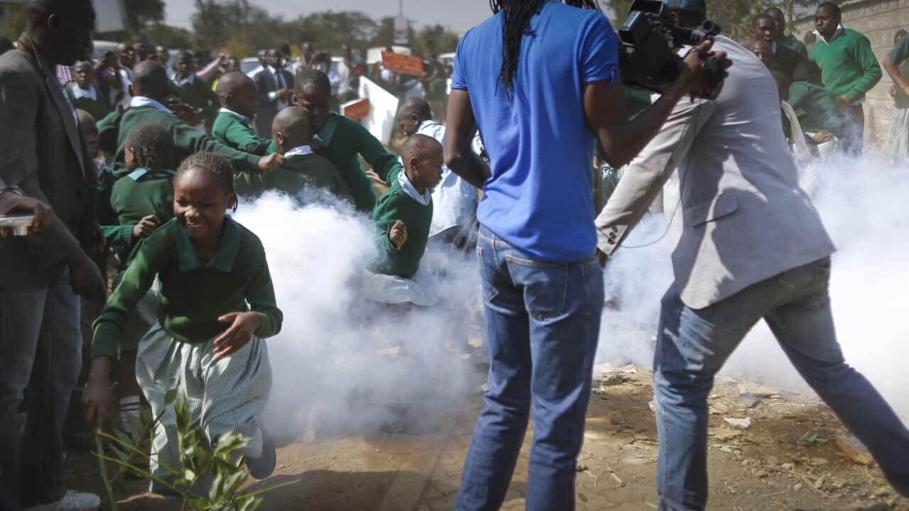 School children flee as a teargas canister is fired by police in front of the school playground during a protest (EPA/DAI KUROKAWA)
