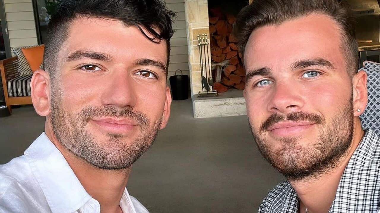 Two men pose for a selfie.