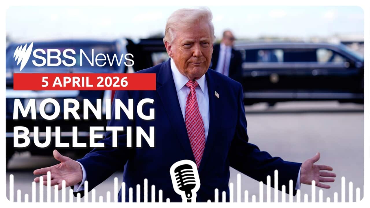 Donald Trump standing in front of a car with arms gesturing outwards.