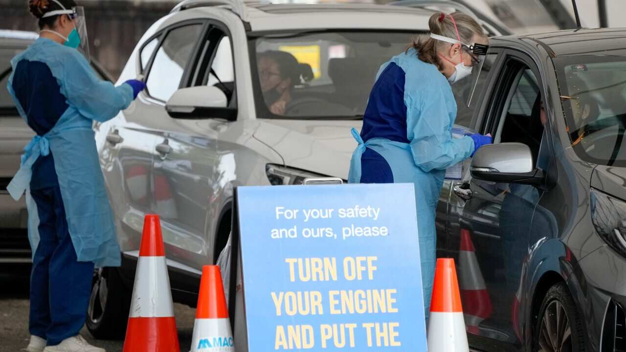 Staff collect samples at a drive-through COVID-19 testing clinic at Bondi Beach in Sydney, Australia, Saturday, Jan. 8, 2022. Australia's most populous state has reinstated some restrictions and suspended elective surgeries as COVID-19 cases surged to ano