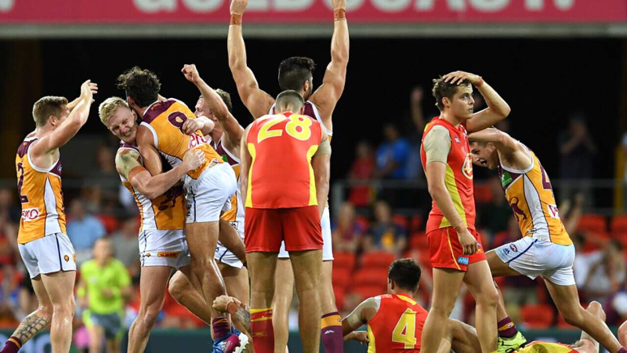 Brisbane Lions players celebrate defeating the Gold Coast Suns