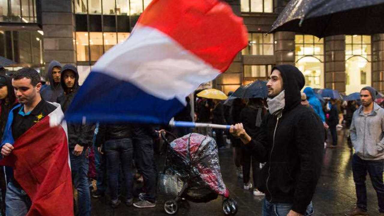 A Sydney resident waves the French flag at a vigil in Martin Place on November 14, 2015