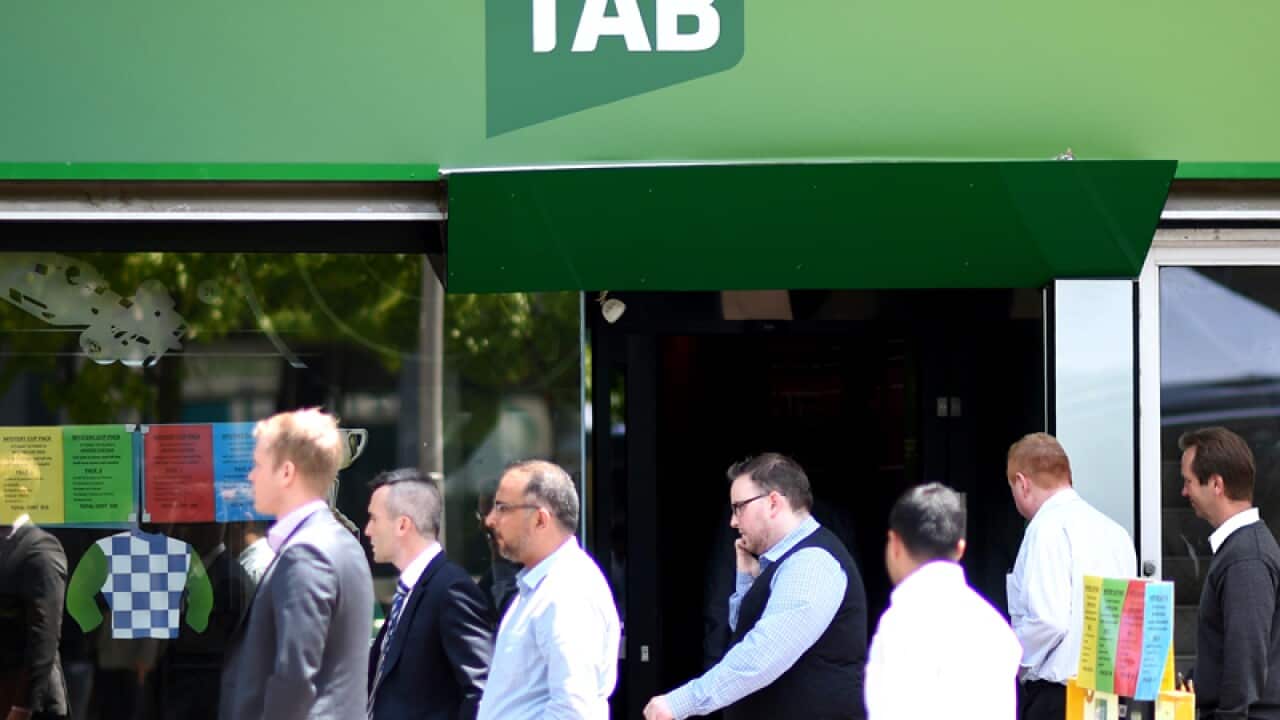 Men are seen walking past a TAB betting branch in Canberra