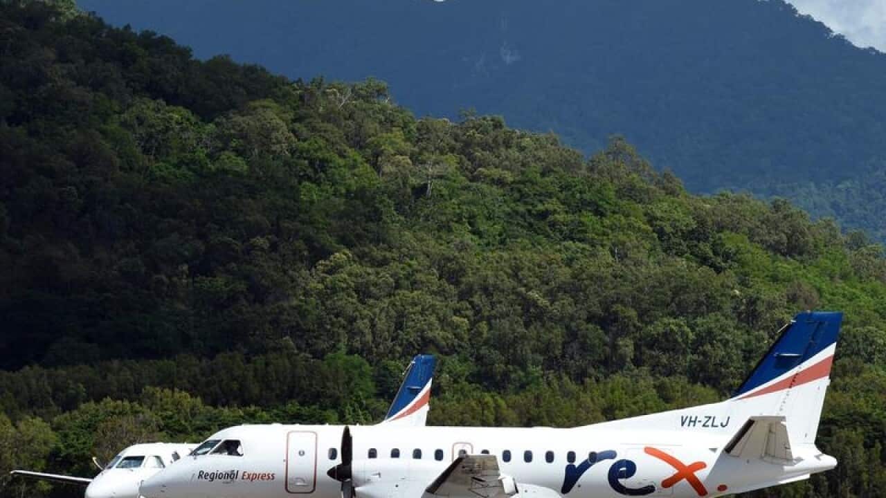 Rex plane on tarmac at Cairns Airport with mouuntains in background