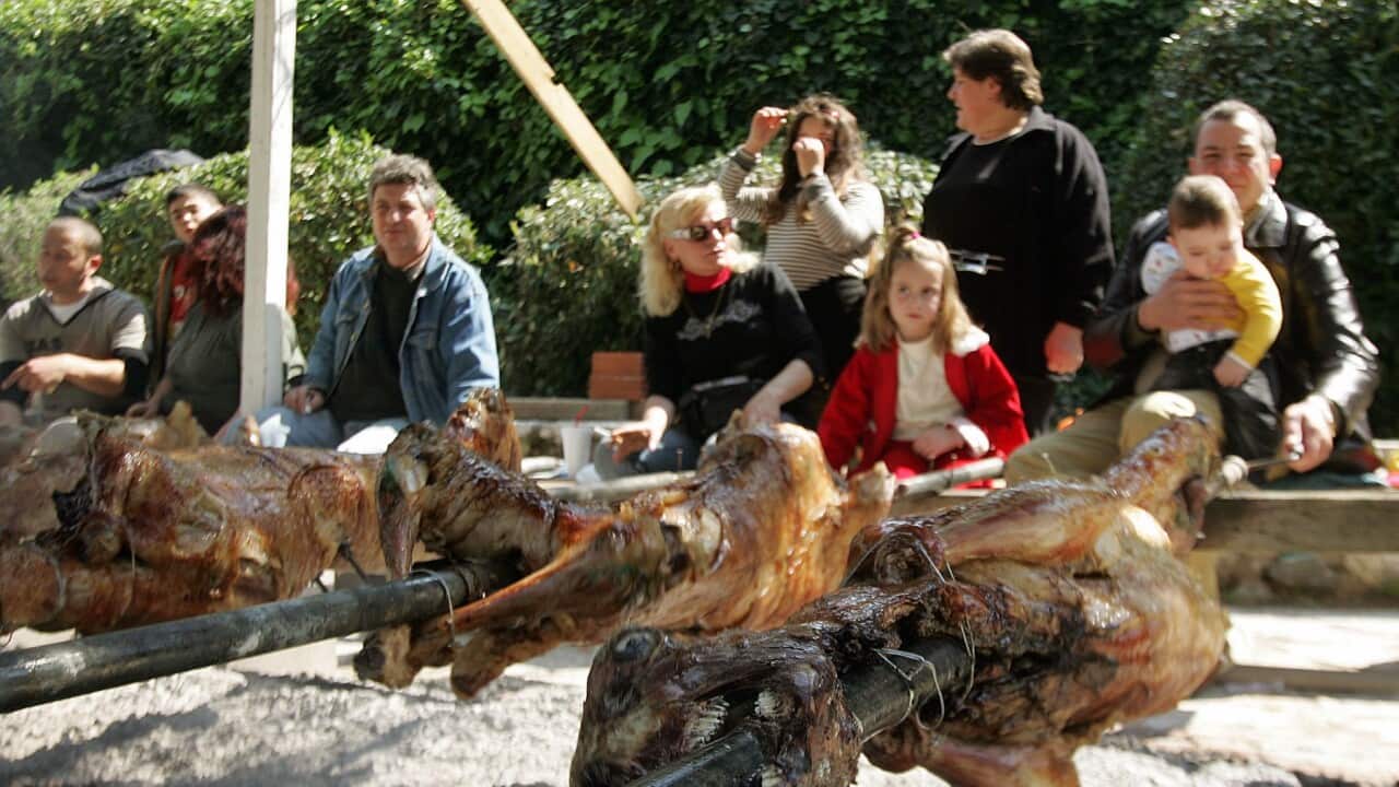 people gathered around lamb on spit