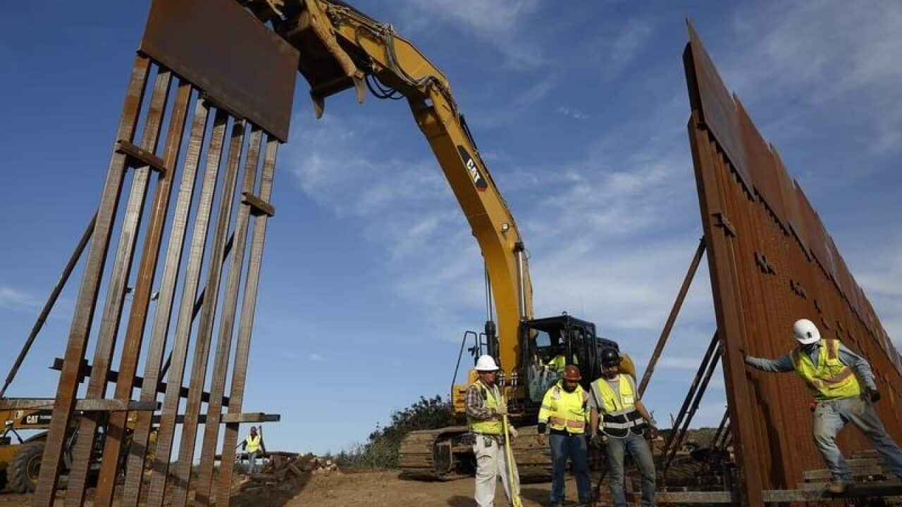 Construction crews install new border wall sections seen from Tijuana.