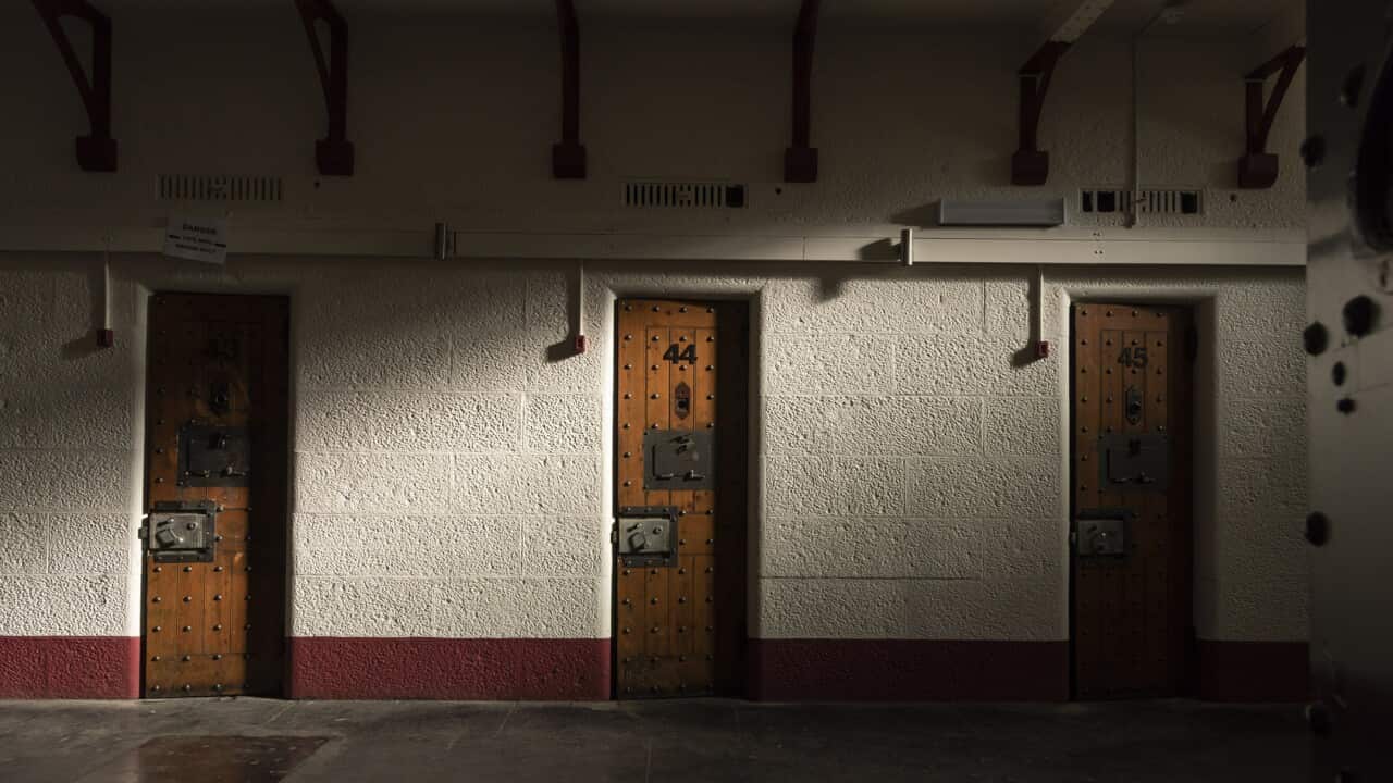 The wooden doors of three prison cells.