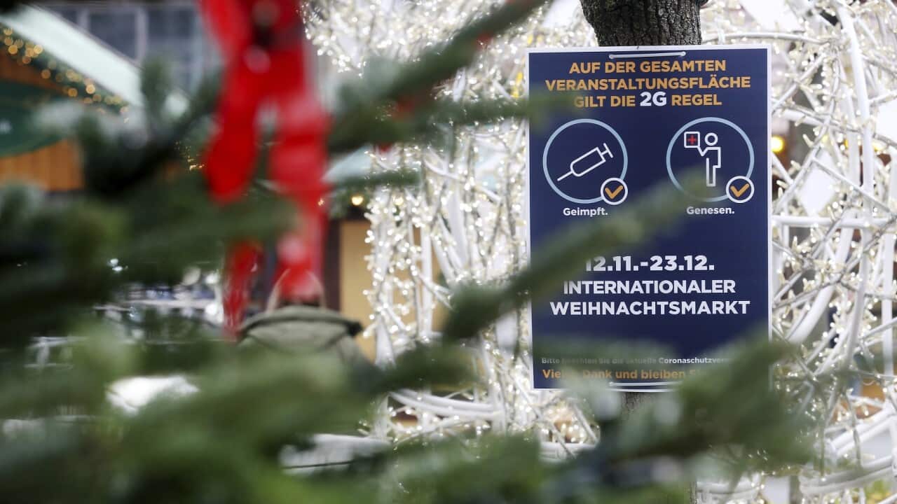 A sign indicating COVID-19 restrictions at the entrance of a Christmas market in Essen, Germany