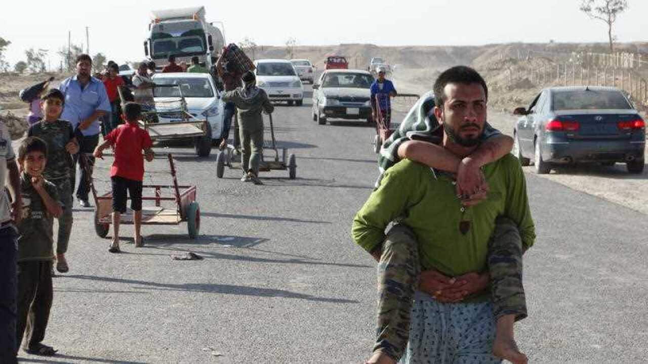 Iraqi family members who left their hometown of Ramadi walk towards Baghdad, outside Ramadi (AAP)